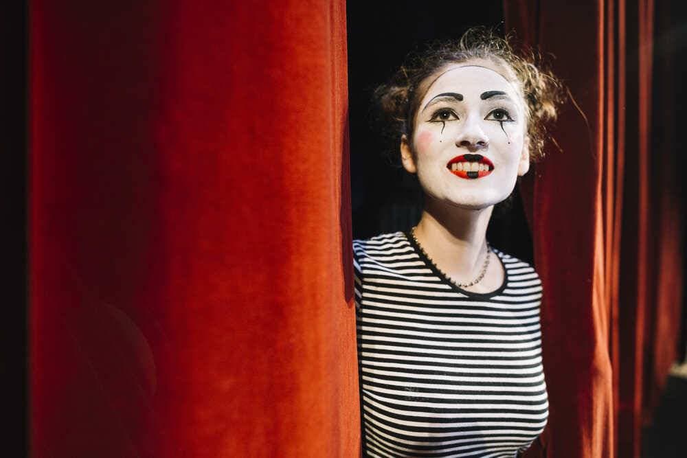 mime-femme-réfléchie-debout-près-du-rideau-rouge