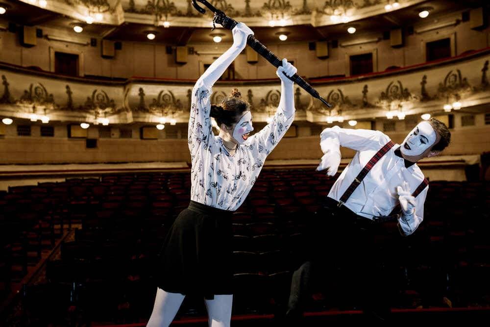 artiste-mime-femme-frappant-mime-homme-avec-parapluie-auditorium